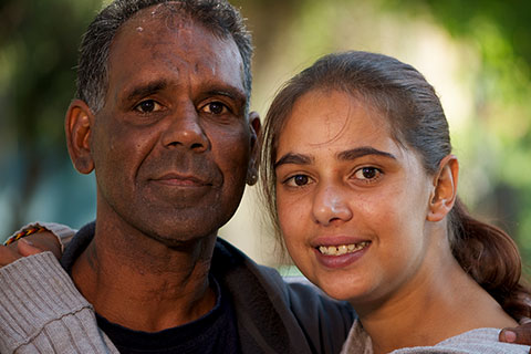 Older man and adolescent girl in grey jumper hugging and smiling