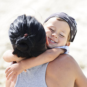 Young boy with bandana headband hugging older woman outside