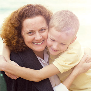 Older woman and young boy with yellow t-shirt smiling and hugging