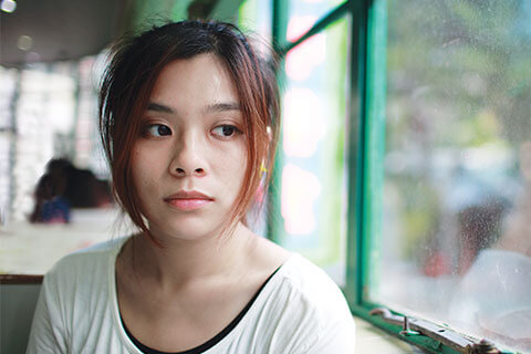 Young teenage girl in a cafe by the window looking outside