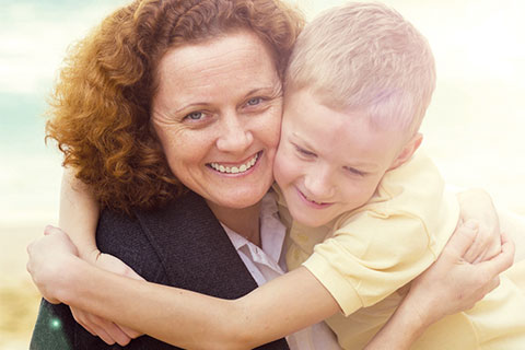 Older woman and young boy with yellow t-shirt smiling and hugging