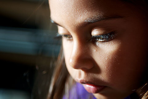 Young girl in purple t-shirt looking down and sad