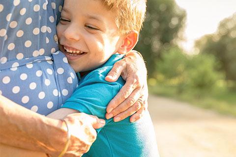 young boy in blue t-shirt hugging older woman