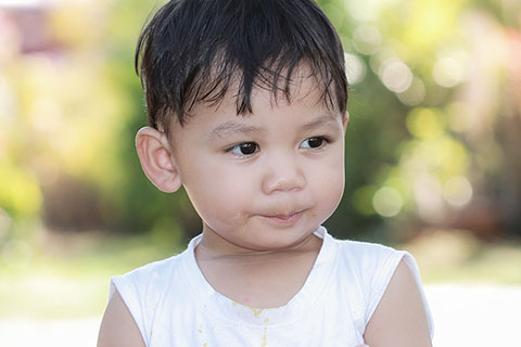 Young asian boy with white top on looking away outside