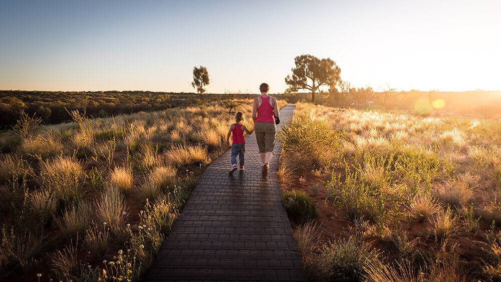 Young girl and older woman walking on a track outside in Australian bush