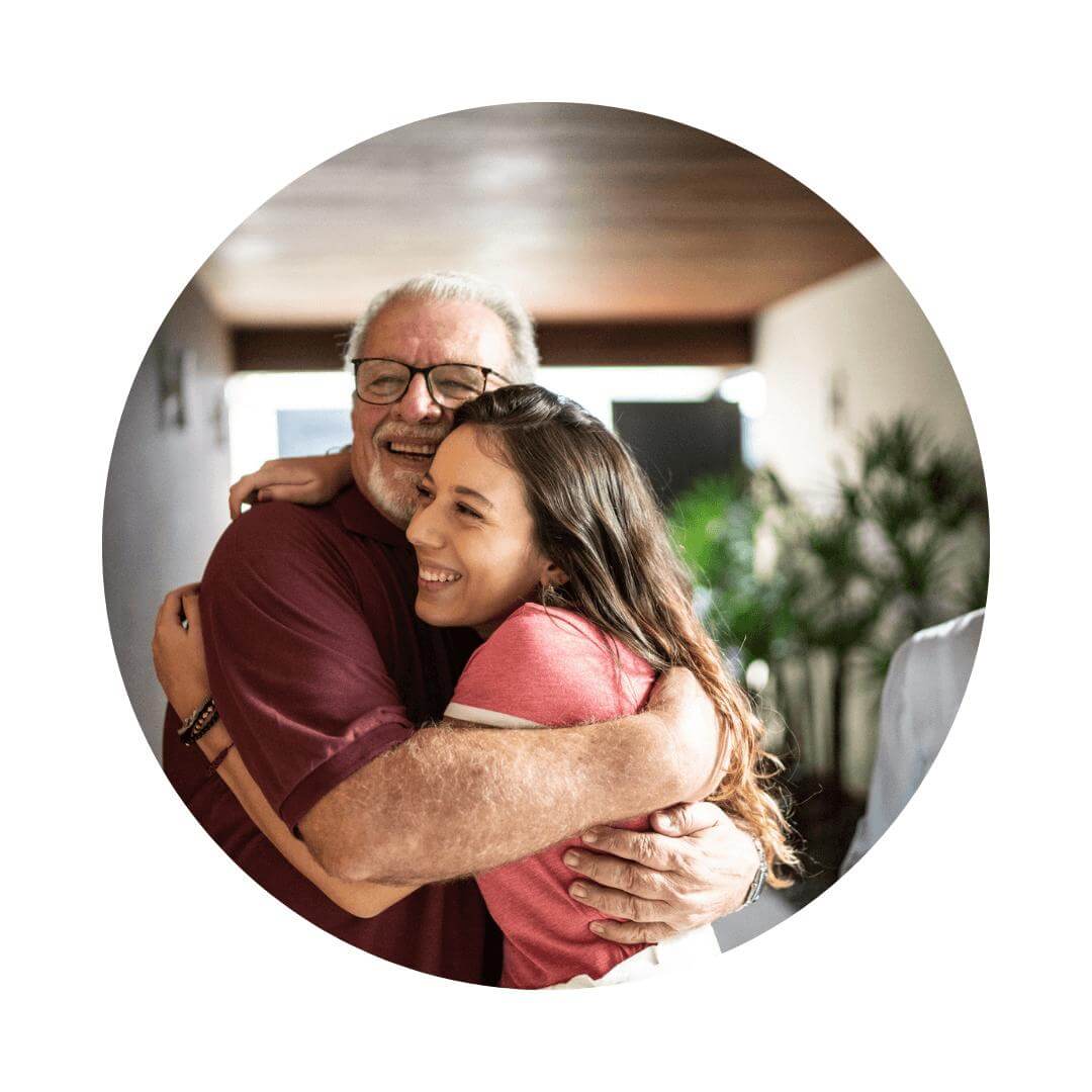 Elderly man embracing a warm hug with a young family member both smiling