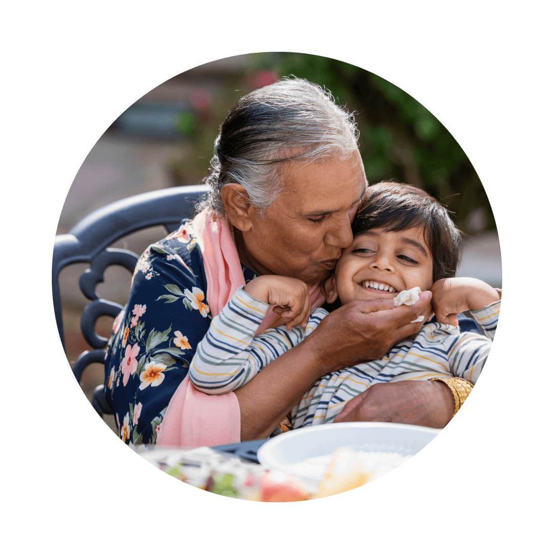 Older woman holding a young child kissing him and trying to wipe his face