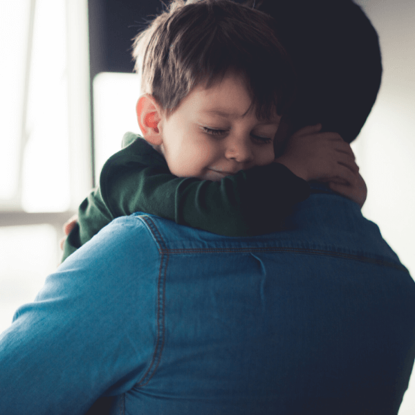 Boy hugging older man in blue jean shirt